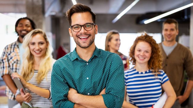 Happy group of employees smiling and socializing together in an office.