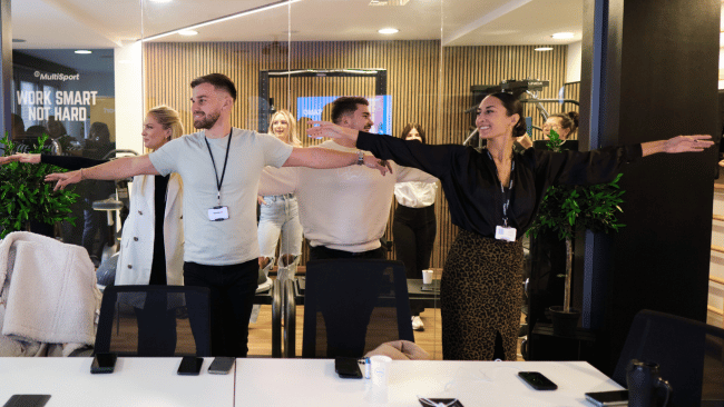 A group of employees stretching together in the office during a work break.